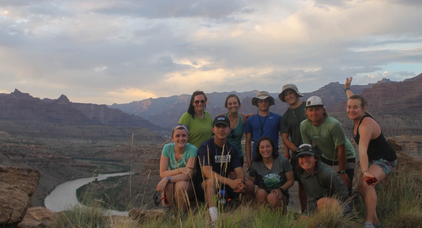 A group of students pose for a photo on an overlook above a winding river